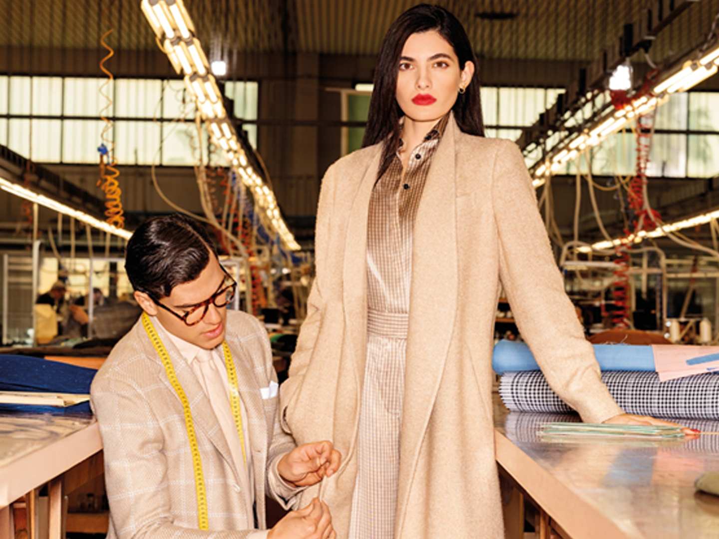 Woman being fitted for a bespoke coat by a tailor in a tailoring workshop